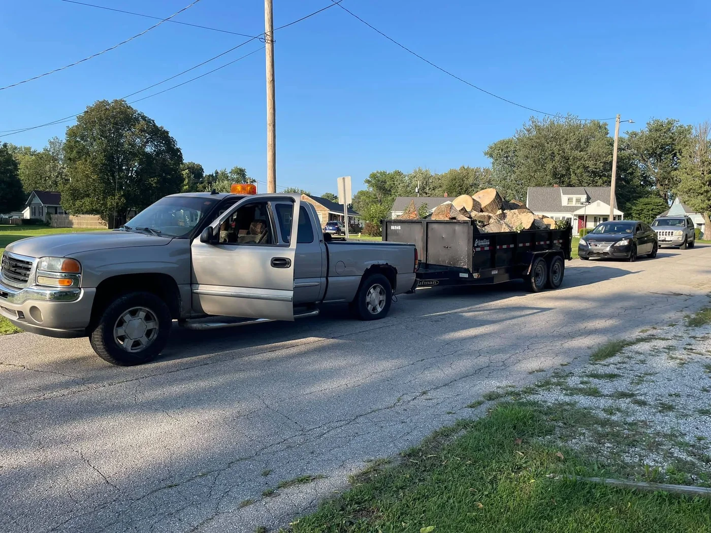 Pickup truck and trailer loaded with cut logs for hauling